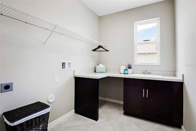 clothes washing area featuring hookup for an electric dryer, washer hookup, cabinets, sink, and light tile patterned floors