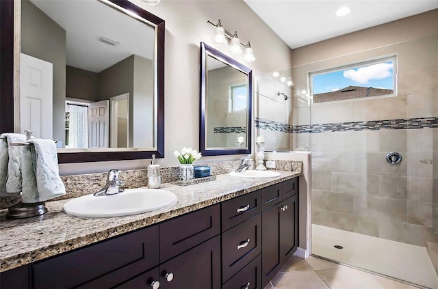 bathroom featuring tiled shower, vanity, and tile patterned flooring