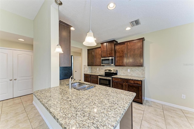 kitchen with kitchen peninsula, appliances with stainless steel finishes, a textured ceiling, sink, and hanging light fixtures