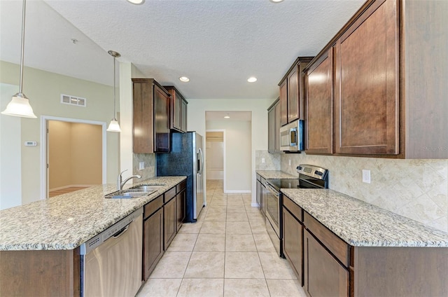 kitchen featuring sink, hanging light fixtures, light stone counters, backsplash, and appliances with stainless steel finishes