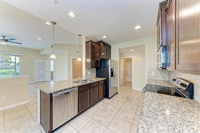 kitchen with hanging light fixtures, sink, light stone countertops, appliances with stainless steel finishes, and tasteful backsplash