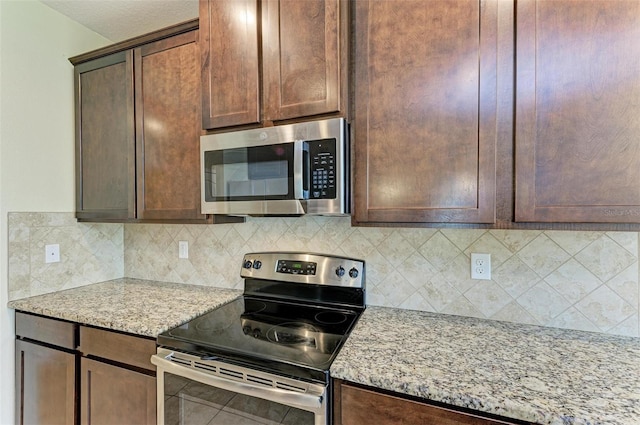 kitchen with light stone countertops, appliances with stainless steel finishes, and tasteful backsplash