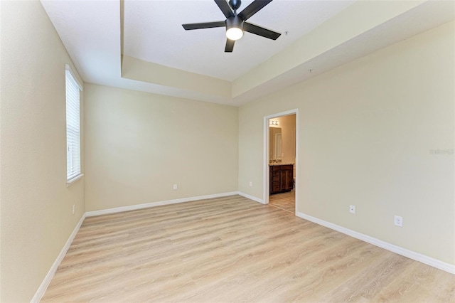 unfurnished room with ceiling fan, a raised ceiling, and light hardwood / wood-style flooring