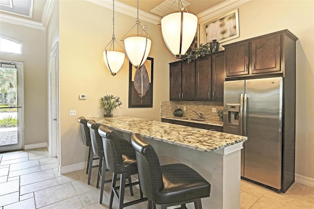 kitchen featuring pendant lighting, backsplash, kitchen peninsula, and stainless steel refrigerator with ice dispenser