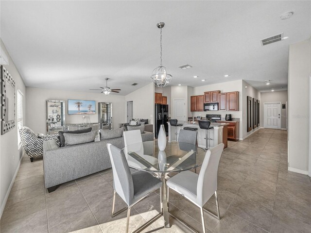 tiled dining area with a healthy amount of sunlight and ceiling fan with notable chandelier