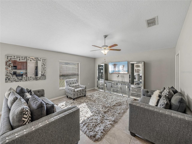 living room featuring ceiling fan, light tile patterned flooring, and a textured ceiling