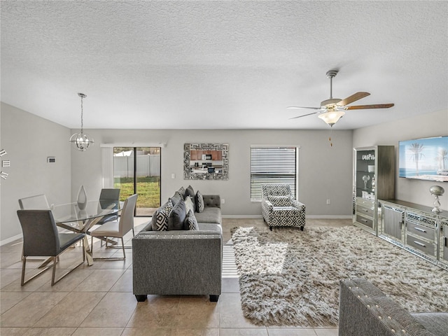 living room with light tile patterned floors, ceiling fan with notable chandelier, a textured ceiling, and plenty of natural light