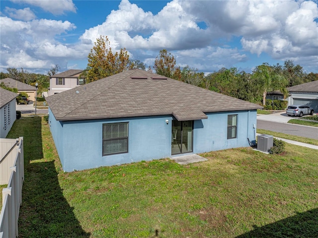 rear view of property featuring cooling unit and a lawn