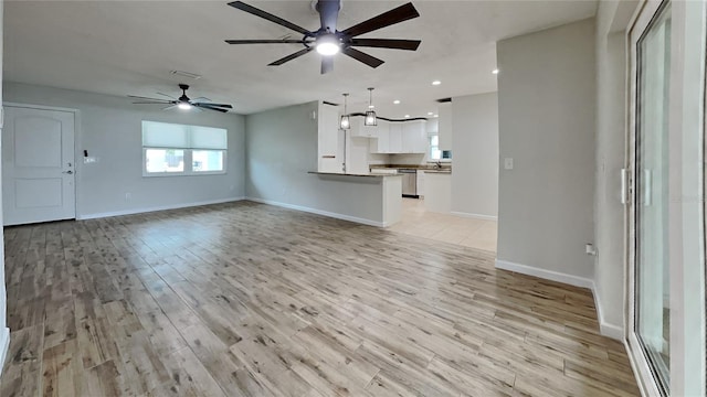 unfurnished living room featuring light wood-type flooring, ceiling fan, and sink