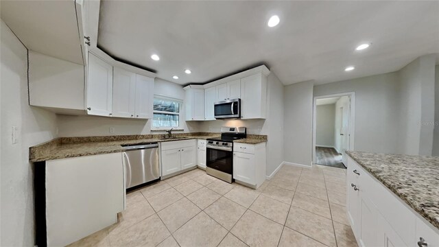 kitchen featuring white cabinets, stainless steel appliances, light stone countertops, and sink