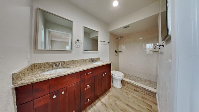 bathroom featuring tiled shower, wood-type flooring, vanity, and toilet