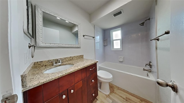 full bathroom featuring vanity, tiled shower / bath, wood-type flooring, and toilet