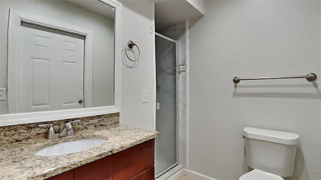 bathroom featuring vanity, toilet, and a shower with door