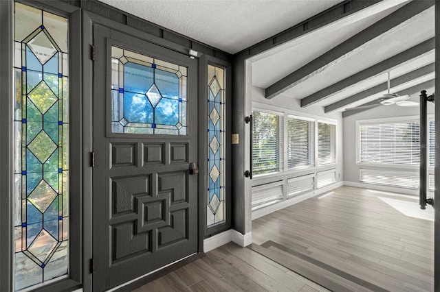 entrance foyer with a textured ceiling, ceiling fan, lofted ceiling with beams, and wood-type flooring