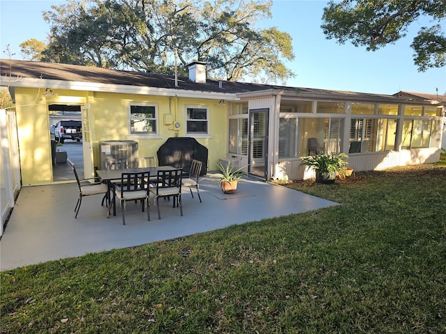 rear view of property featuring a yard, a patio area, and a sunroom