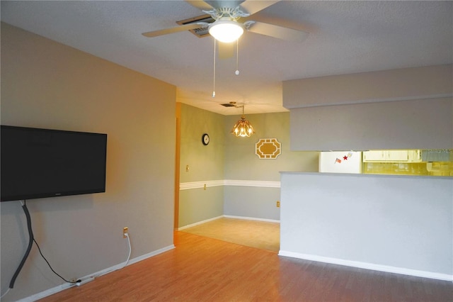 spare room with wood-type flooring and ceiling fan with notable chandelier