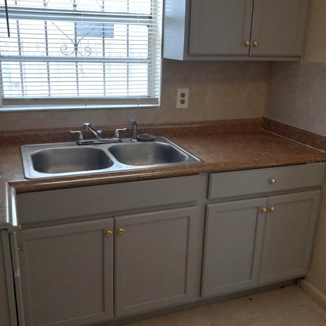 kitchen featuring gray cabinetry, sink, and tasteful backsplash