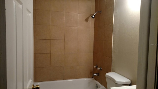 bathroom featuring toilet and tiled shower / bath