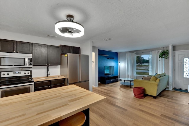 kitchen featuring dark brown cabinetry, light hardwood / wood-style flooring, stainless steel appliances, and sink