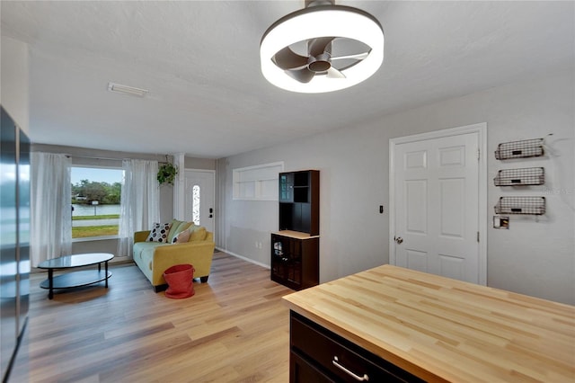 interior space with stainless steel fridge, ceiling fan, light hardwood / wood-style floors, and a textured ceiling