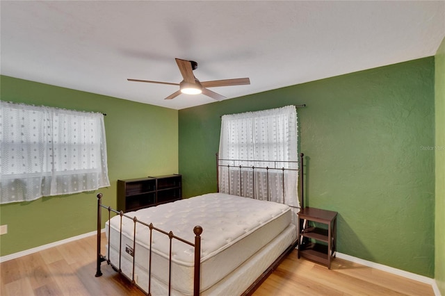 bedroom featuring hardwood / wood-style floors, ceiling fan, and multiple windows