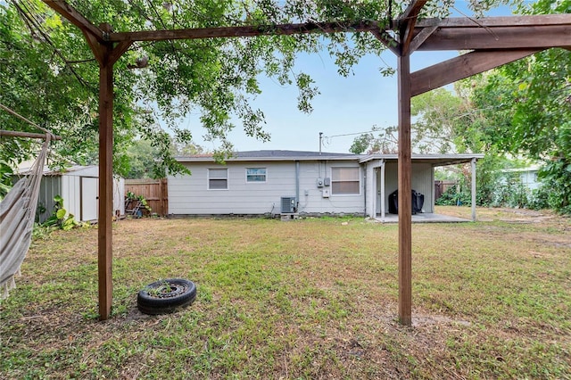 rear view of property featuring a lawn, cooling unit, and a storage shed