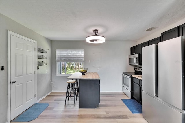 6524 14th St N, Saint Petersburg, FL 33702 - kitchen featuring stainless steel appliances, light countertops, light wood-style floors, dark cabinets, and a textured ceiling