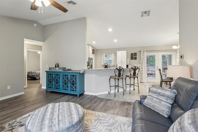 living room with ceiling fan, high vaulted ceiling, french doors, and hardwood / wood-style floors