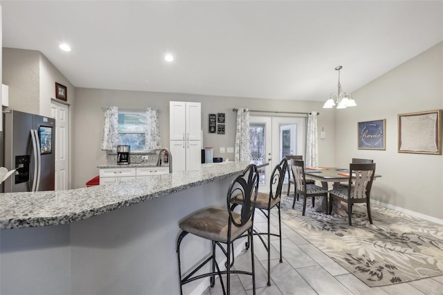 kitchen with white cabinets, stainless steel fridge with ice dispenser, light stone counters, and pendant lighting