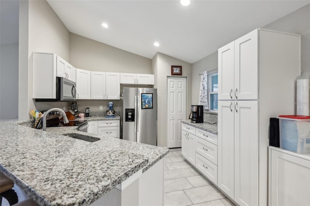 kitchen featuring a breakfast bar area, stainless steel appliances, light stone countertops, white cabinets, and kitchen peninsula