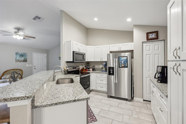 kitchen with appliances with stainless steel finishes, light stone countertops, white cabinets, sink, and kitchen peninsula