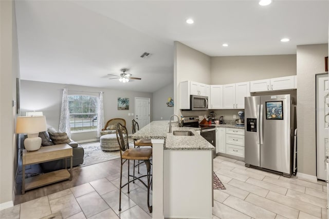 kitchen featuring appliances with stainless steel finishes, sink, a breakfast bar, kitchen peninsula, and white cabinets