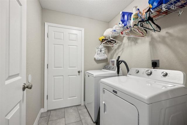 laundry area with light tile patterned floors, washer and dryer, and a textured ceiling