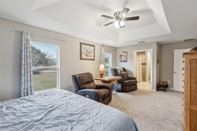 carpeted bedroom featuring ensuite bathroom, ceiling fan, and a raised ceiling