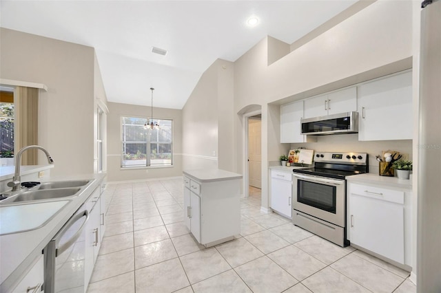 kitchen featuring appliances with stainless steel finishes, white cabinets, a center island, hanging light fixtures, and lofted ceiling