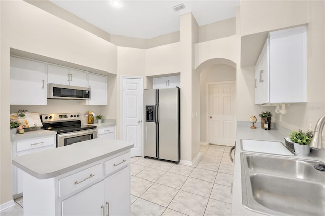 kitchen featuring appliances with stainless steel finishes, sink, white cabinets, a center island, and light tile patterned flooring