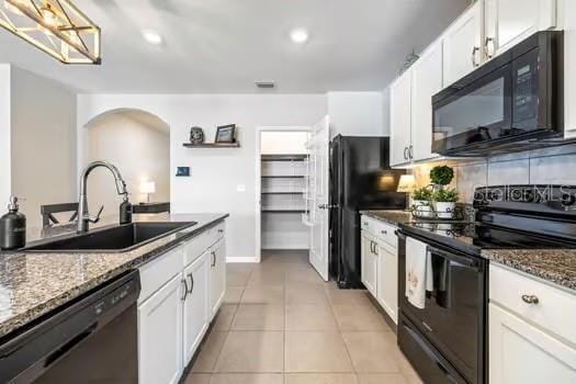 kitchen featuring white cabinets, sink, dark stone countertops, and black appliances