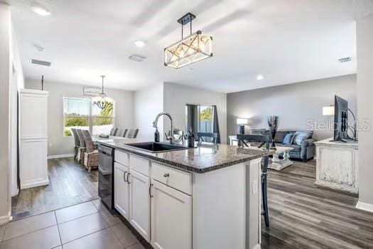 kitchen with white cabinets, stainless steel dishwasher, a wealth of natural light, and an island with sink