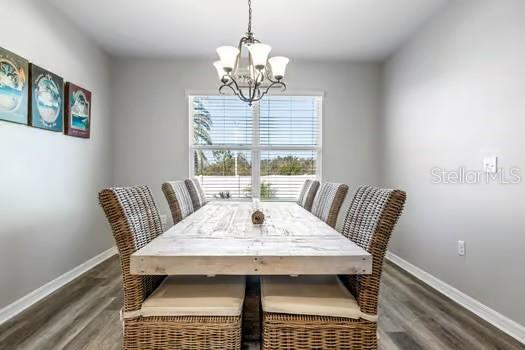 dining area with dark wood-type flooring and an inviting chandelier