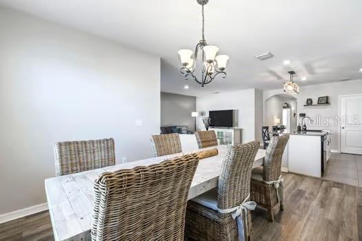 dining space featuring wood-type flooring and an inviting chandelier