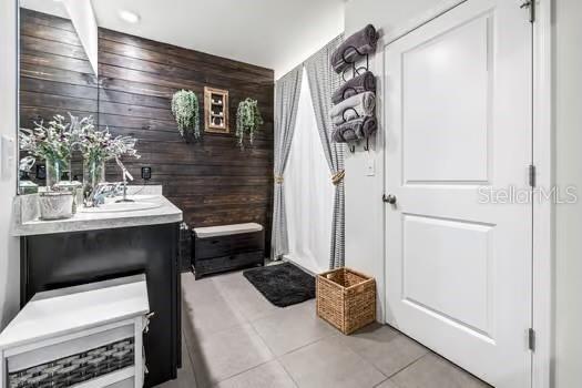 interior space with tile patterned floors, wooden walls, and vanity