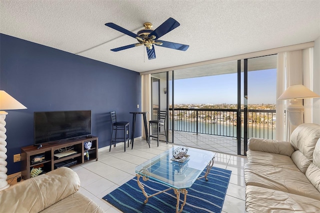 living room with ceiling fan, floor to ceiling windows, light tile patterned floors, and a textured ceiling