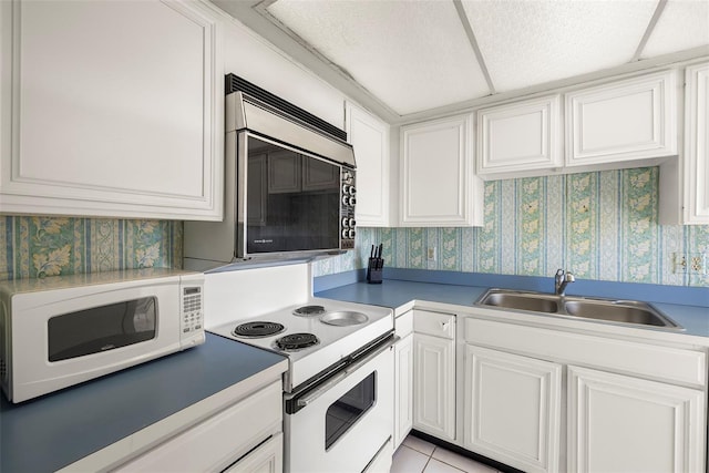 kitchen featuring white cabinetry, sink, light tile patterned floors, and white appliances