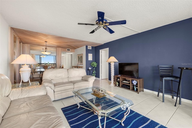 living room with ceiling fan, light tile patterned flooring, and a textured ceiling