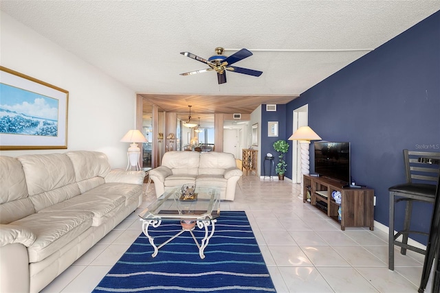 tiled living room featuring ceiling fan and a textured ceiling