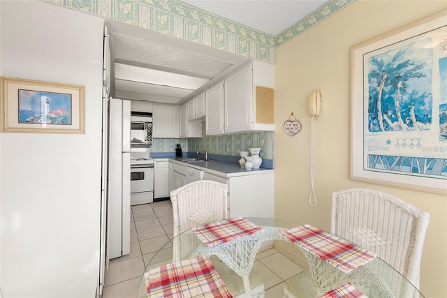 kitchen featuring white appliances, sink, decorative backsplash, light tile patterned floors, and white cabinetry