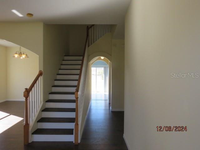 stairs with hardwood / wood-style floors and an inviting chandelier