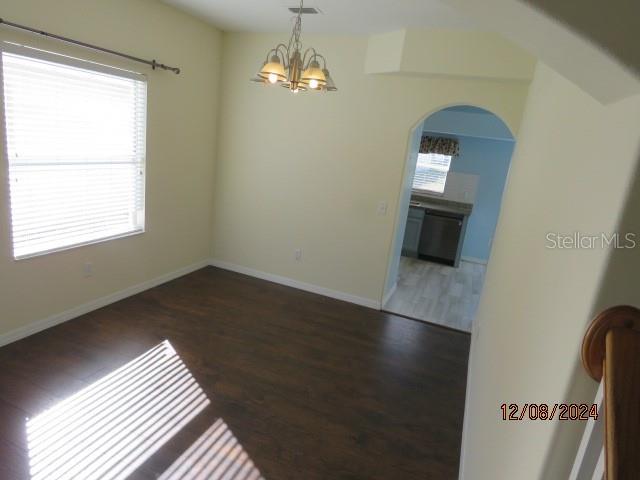 spare room with dark hardwood / wood-style flooring, plenty of natural light, and a chandelier