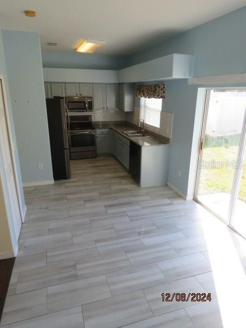 kitchen featuring light wood-type flooring, sink, gray cabinetry, and black appliances