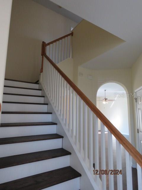 staircase featuring ceiling fan